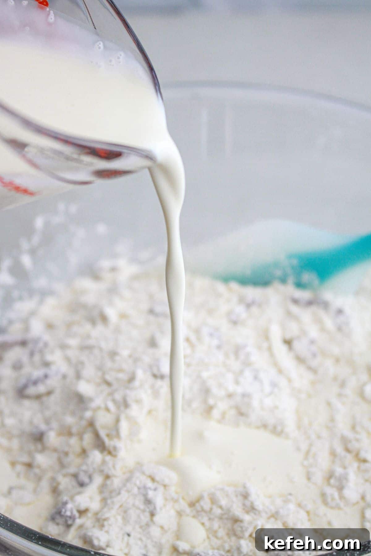 cream being poured into dry ingredients in a mixing bowl.