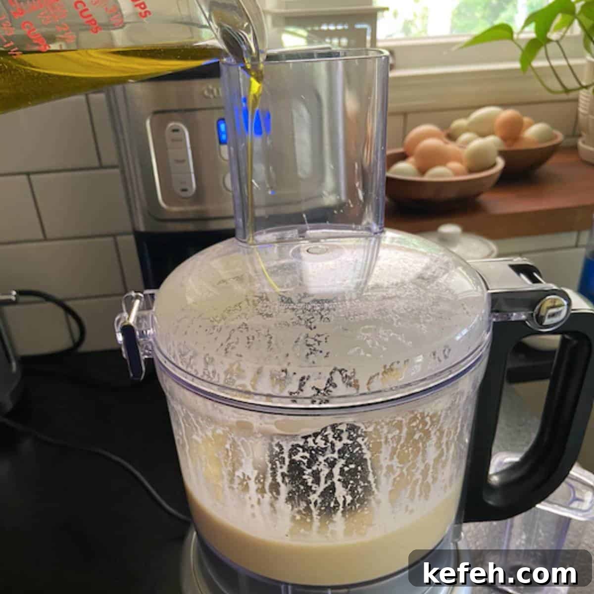 Creamy Caesar Salad Dressing Without Anchovies or Raw Eggs 5 Pouring olive oil into food processor on low speed.
