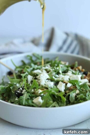 pouring creamy balsamic salad dressing over salad in white bowl