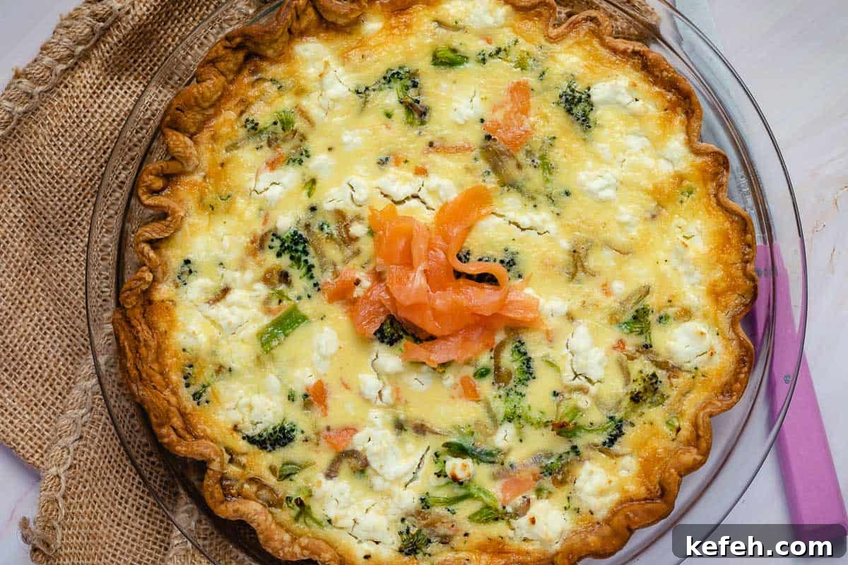 baked salmon and broccoli quiche with smoked salmon on top next to knife and folded burlap.