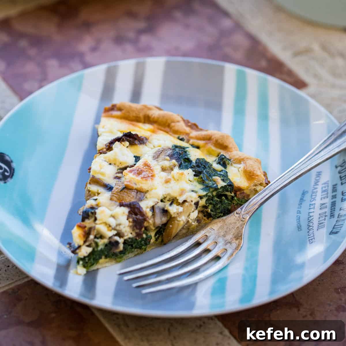 slice of spinach mushroom quiche on plate with fork