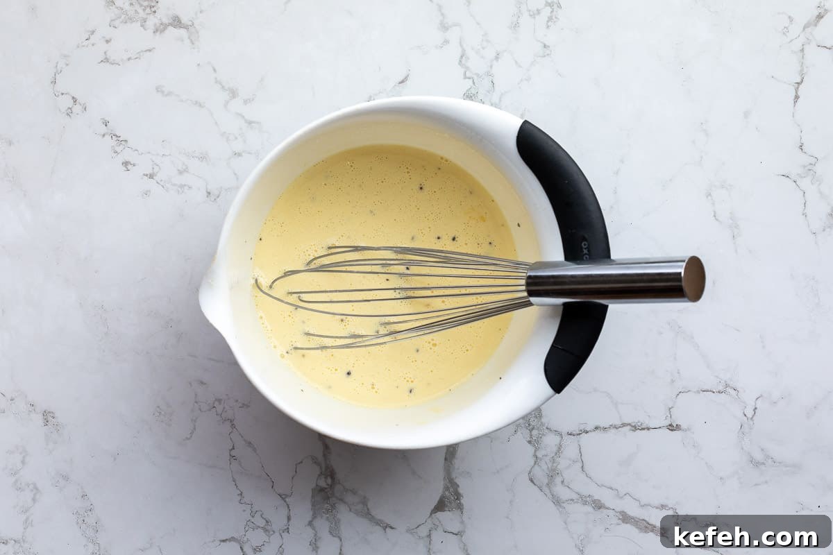 custard for quiche in bowl with whisk.