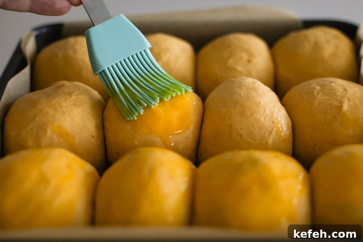 Hand brushing egg wash on top of dough.
