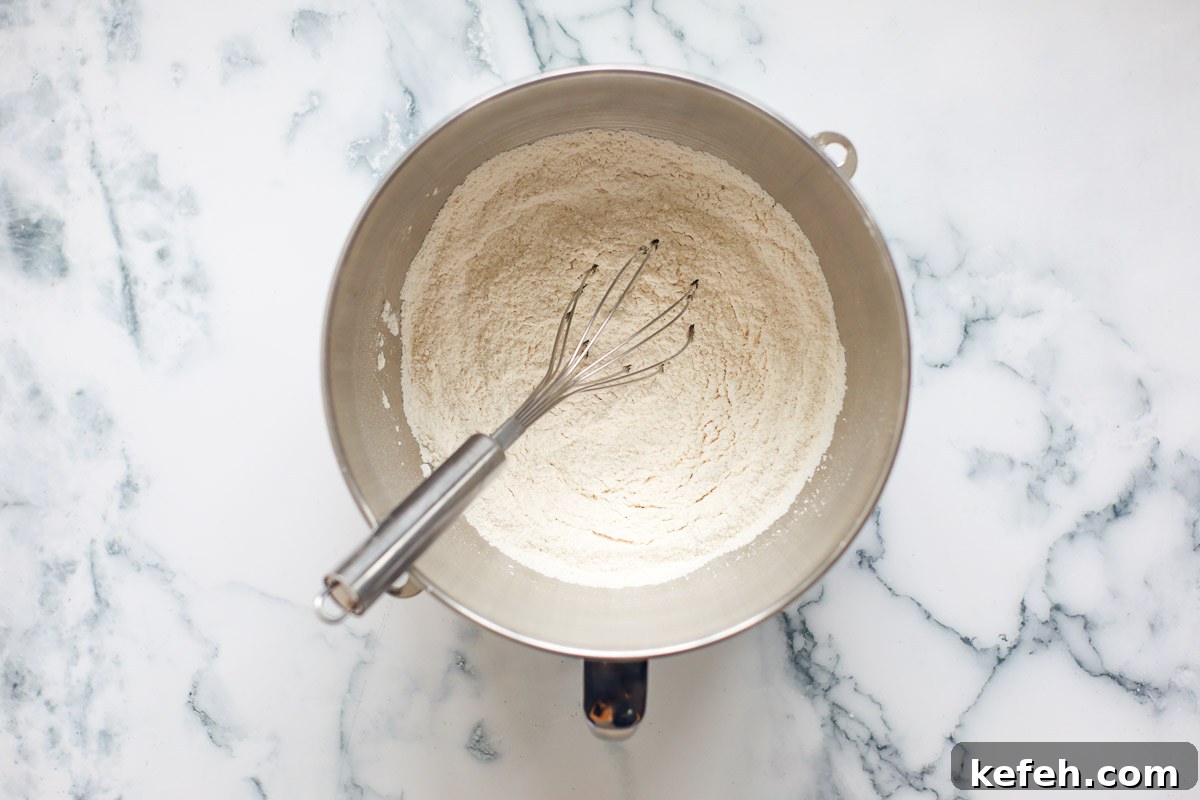 Dry ingredients with whisk inside metal bowl.