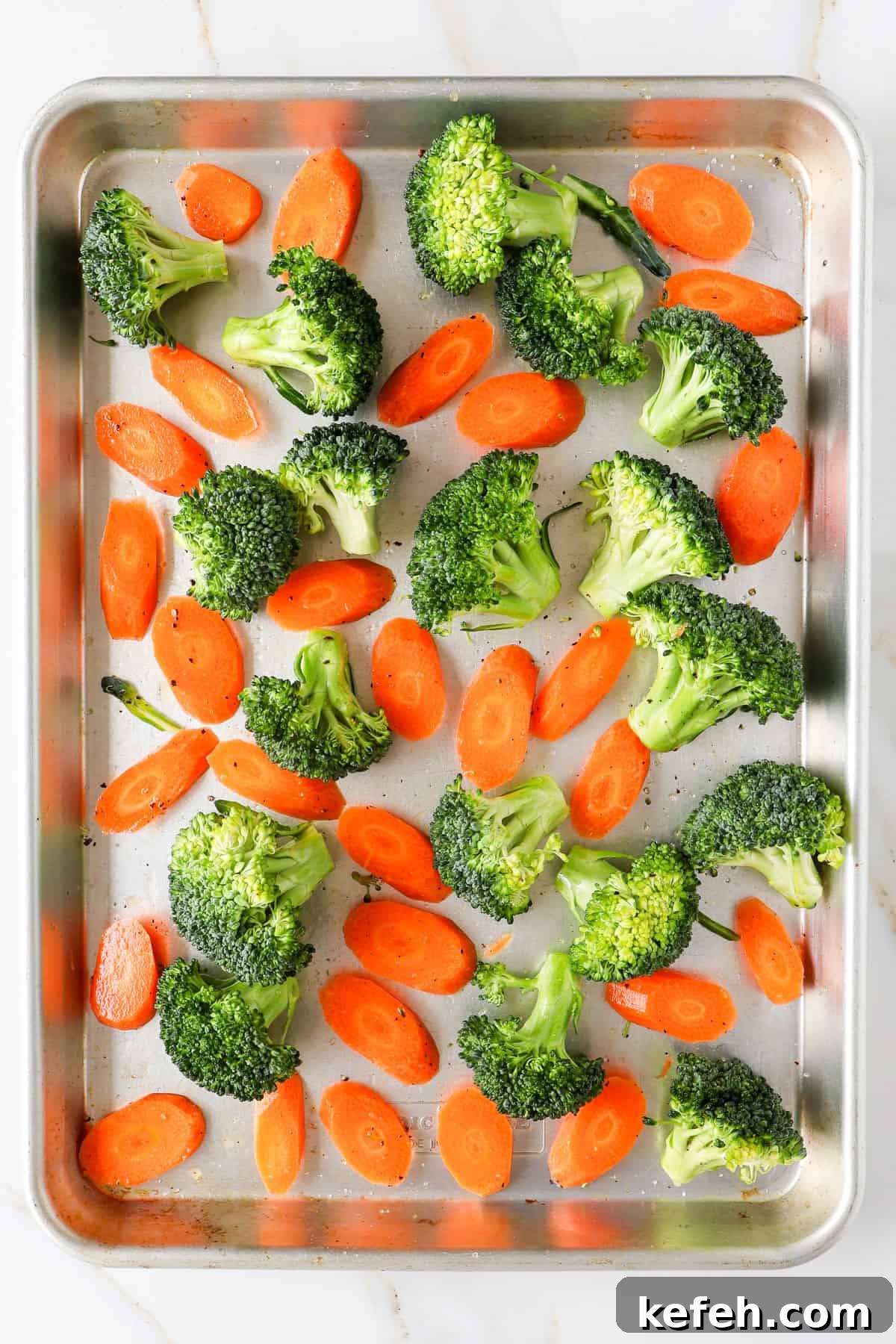 Roasted broccoli and carrots on baking sheet.