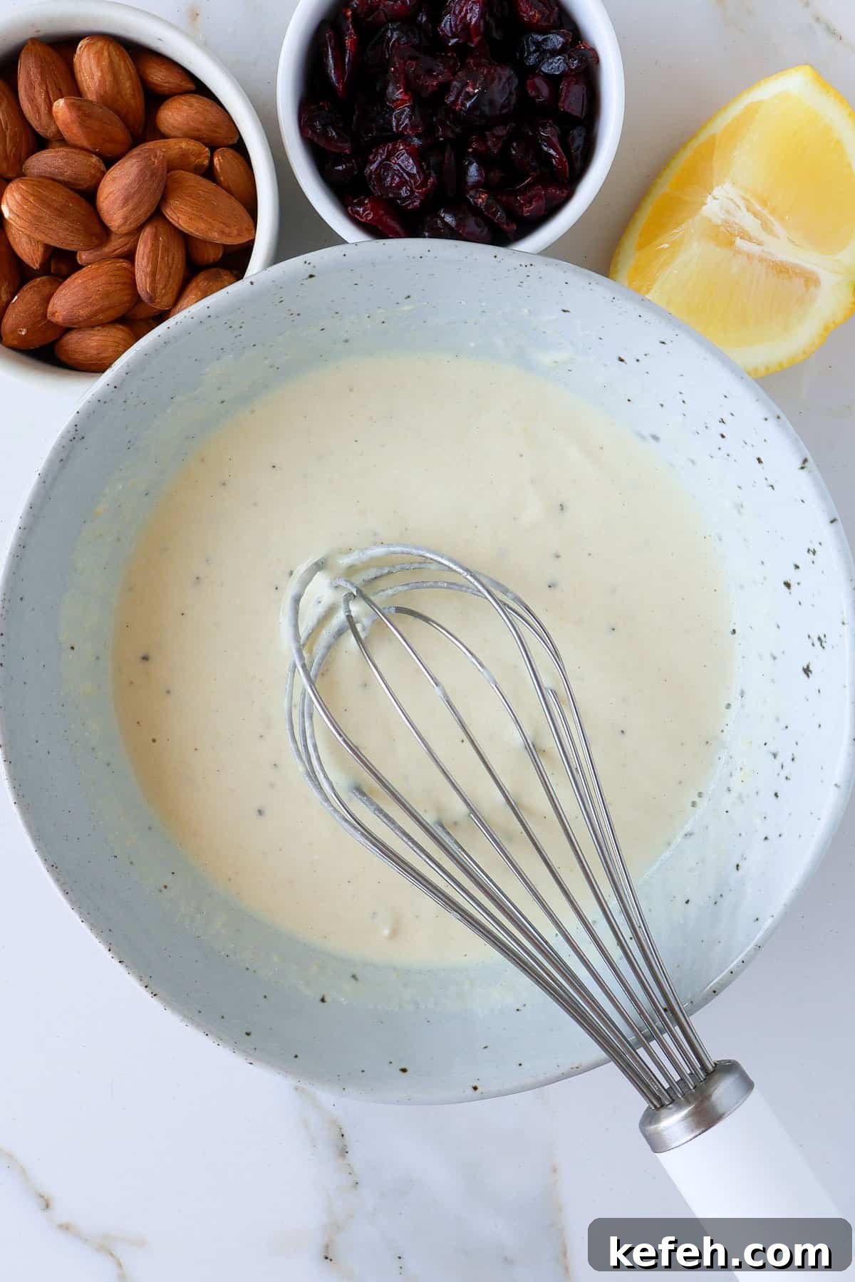 Tahini yoghurt dressing in a bowl with a whisk.