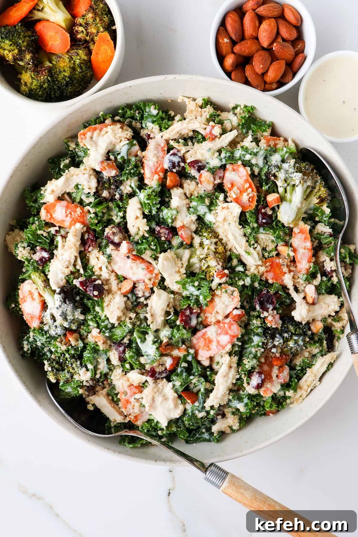Chicken, broccoli and kale salad served in a bowl with spoons scooped in.