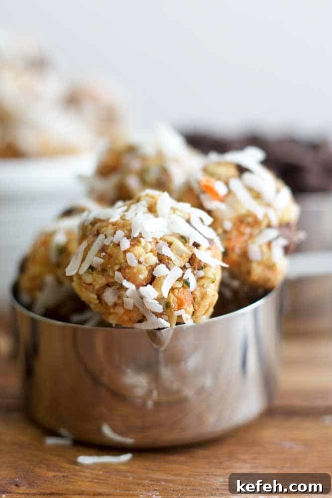 carrot cake energy balls covered in coconut flakes sitting in a metal measuring cup