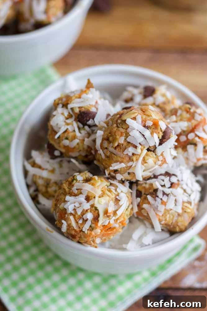 white bowl on a wooden table filled with carrot cake energy balls covered in coconut flakes