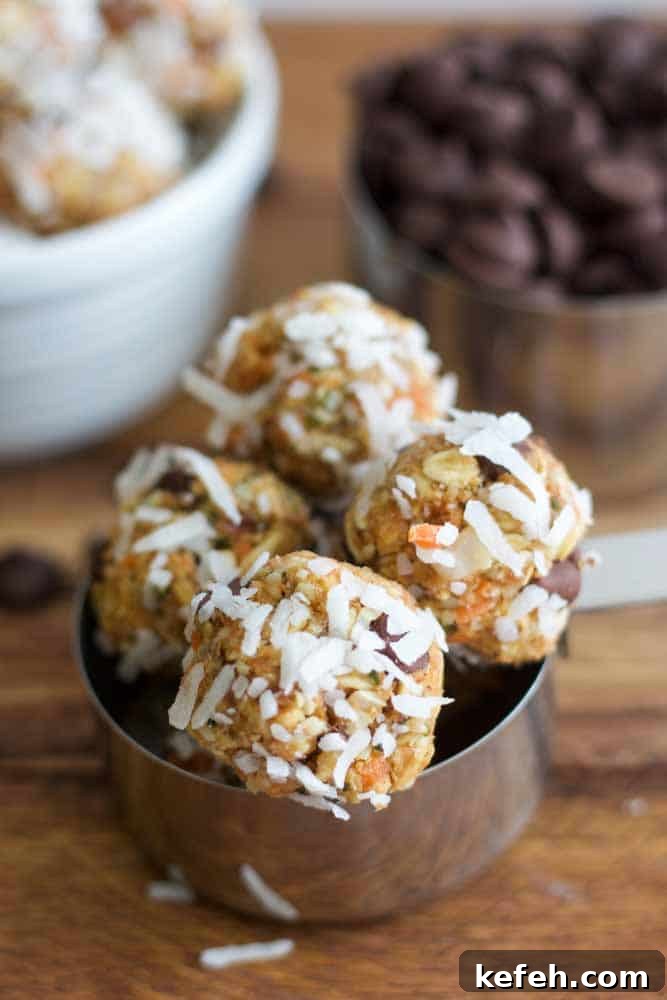carrot cake energy balls covered in coconut flakes sitting in a metal measuring cup resting on a wood table