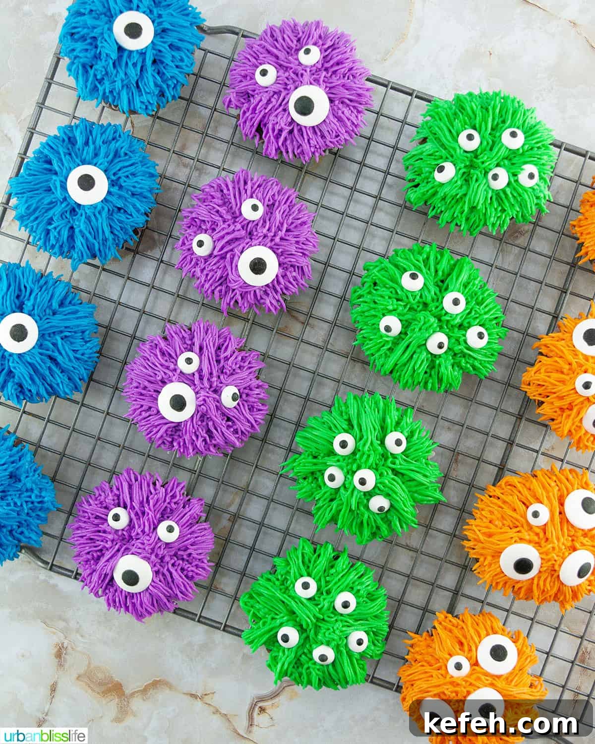 several colorful bright halloween monster cupcakes on a wire rack.