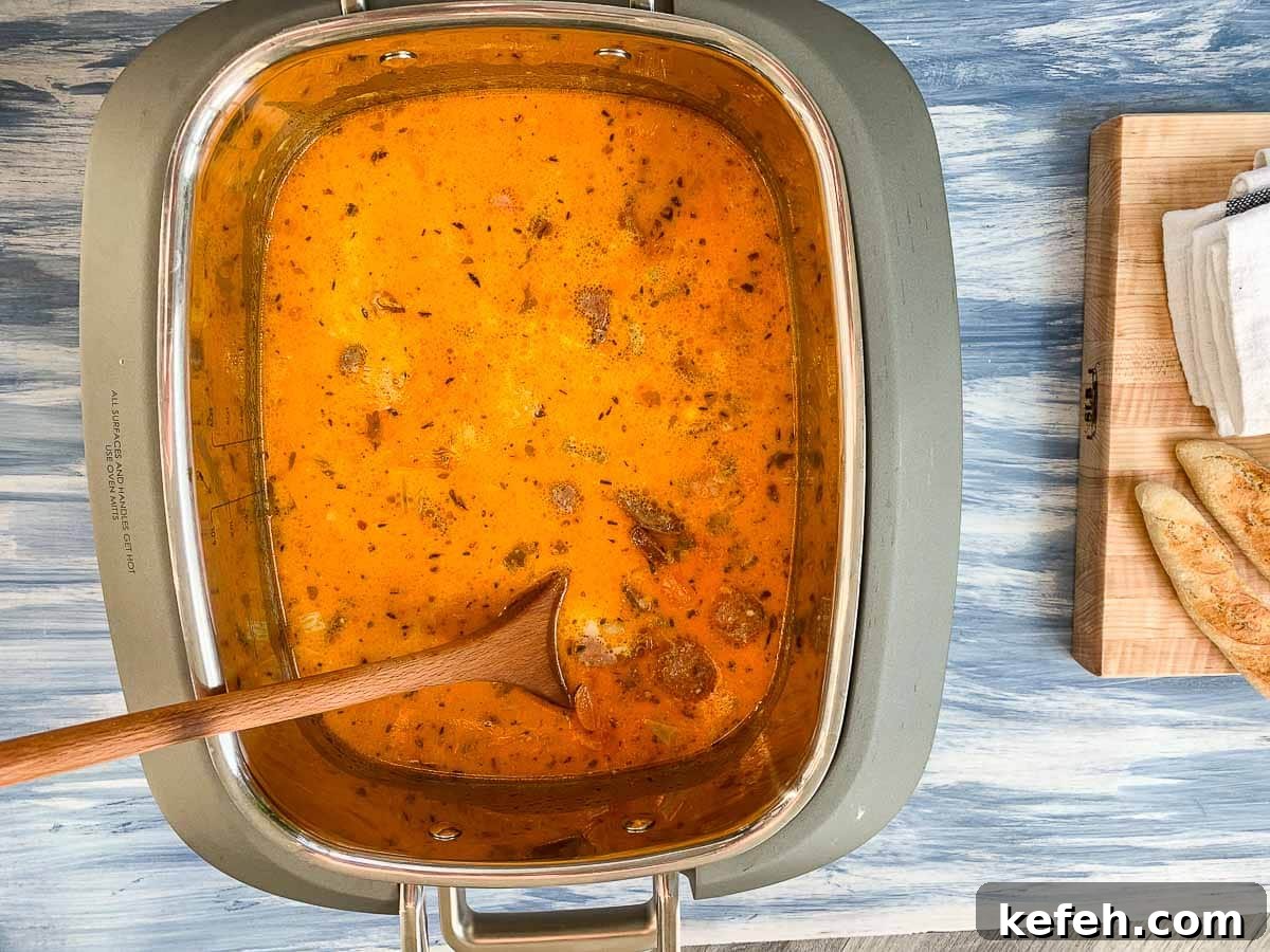 Looking down into a crock pot of creamy sausage and potato soup.