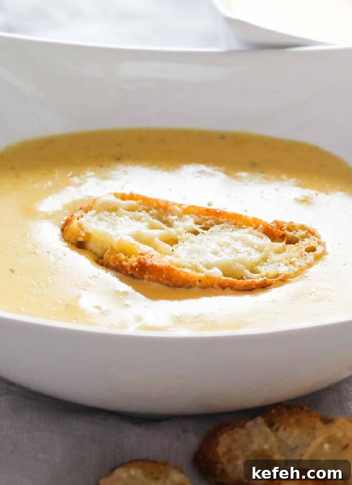 White bowl filled with cheese soup and a homemade crouton on top.