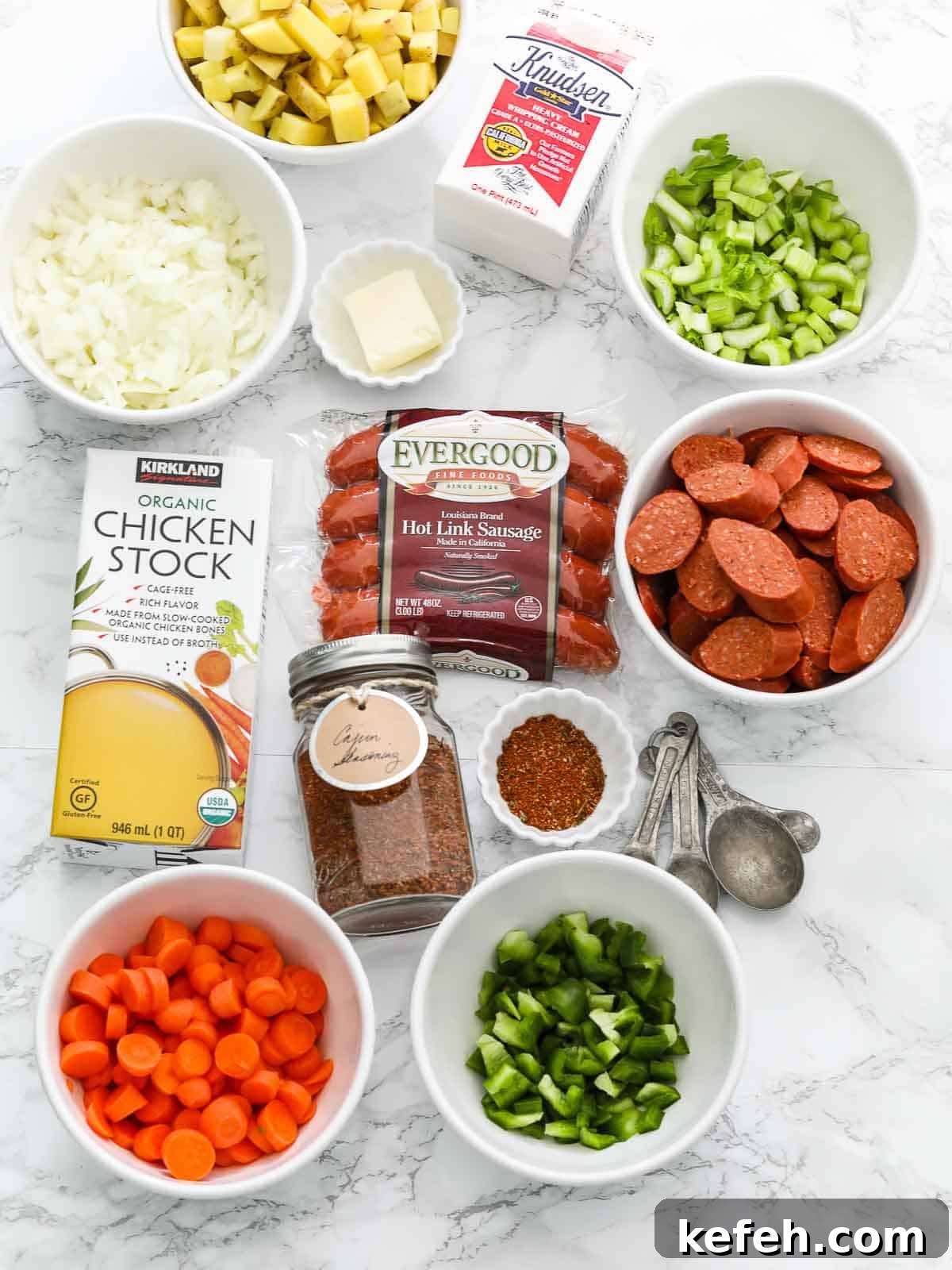 Ingredients on a marble table to make a Cajun sausage potato soup in a crock pot.