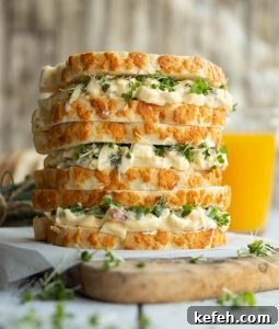 3 sandwiches stacked on each other on wooden chopping board