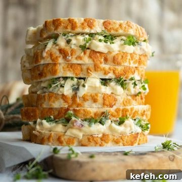 3 sandwiches stacked on each other on wooden chopping board