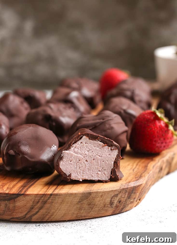 No-Bake Paleo Strawberry Cheesecake Bites Recipe 5 vegan paleo strawberry cheesecake bites on a cutting board with the inside showing with one