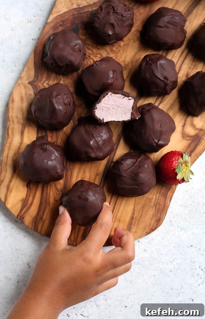 No-Bake Paleo Strawberry Cheesecake Bites Recipe 7 a little hand wrapping a vegan cheesecake bite