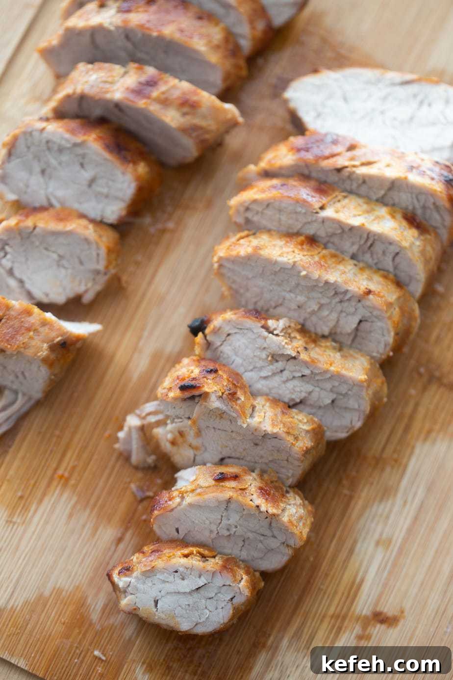Crispy Air Fryer Pork Tenderloin with Garlic Herb Rub 3 Two sliced Air Fryer pork tenderloins on a wooden cutting board.