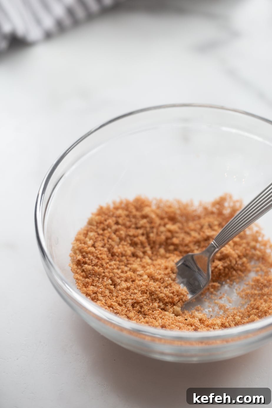 Crispy Air Fryer Pork Tenderloin with Garlic Herb Rub 5 Spice blend for pork tenderloin in a glass bowl being mixed with a fork.