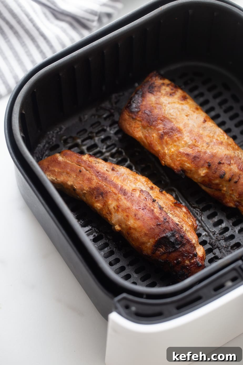 Crispy Air Fryer Pork Tenderloin with Garlic Herb Rub 9 Finished pork tenderloin in an air fryer basket.
