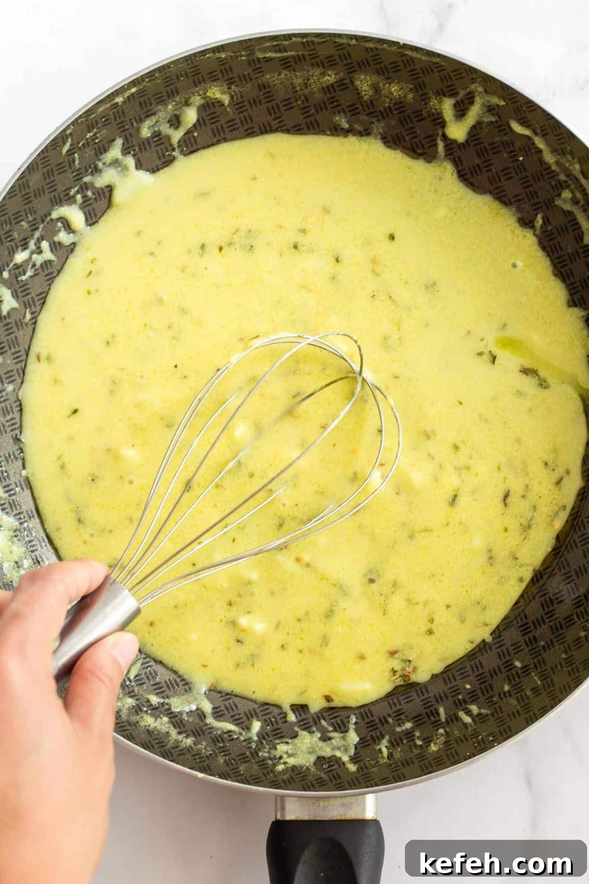 Creamy Dairy-Free Potato Bake (Gluten-Free, Vegan) Whisking pale yellow mixture in skillet.