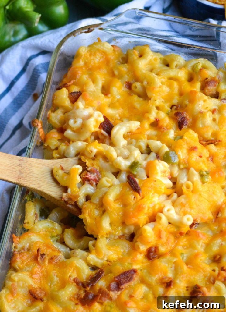 Creamy Pimento Cheese Macaroni and Cheese 2 a wooden spoon scooping pimento cheese macaroni and cheese from a glass baking dish