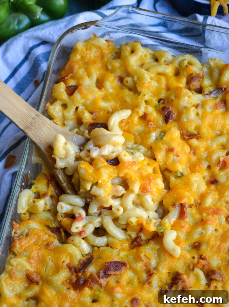 Creamy Pimento Cheese Macaroni and Cheese 5 a wooden spoon scooping pimento cheese macaroni and cheese from a glass baking dish