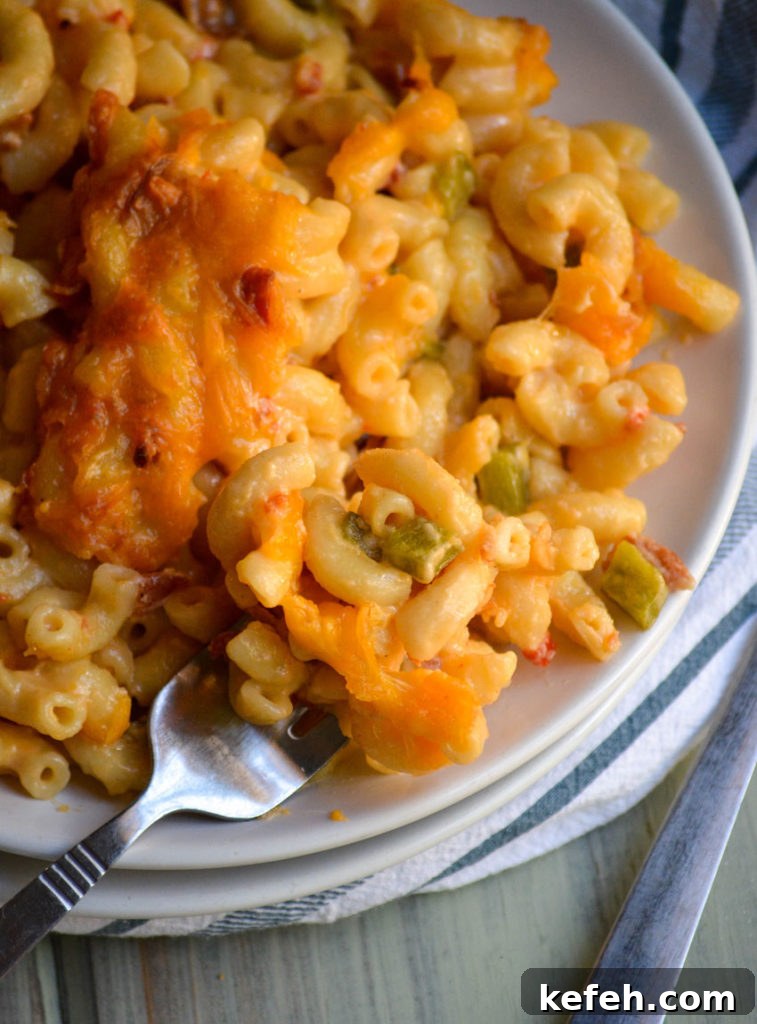 Creamy Pimento Cheese Macaroni and Cheese 7 a silver fork on a white plate with pimento cheese mac and cheese