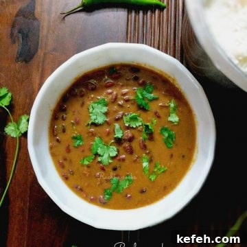 Authentic Punjabi Rajma Masala — Creamy Rajma Curry 2 a pot of brown rajma curry in a white bowl on a brown background