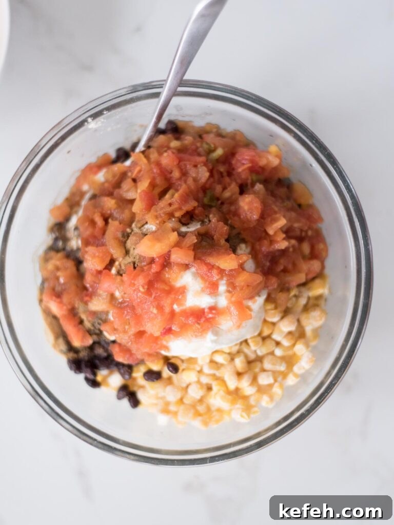 Tex Mex Chicken with Black Beans and Rice Casserole 9 Tomatoes topping the corn and sour cream mixture in a mixing bowl.