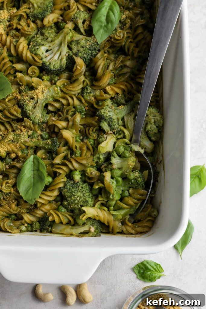 Baked Green Pesto Pasta Casserole Recipe 10 Green Pesto Pasta Casserole in casserole dish topped with basil and vegan parmesan with serving spoon