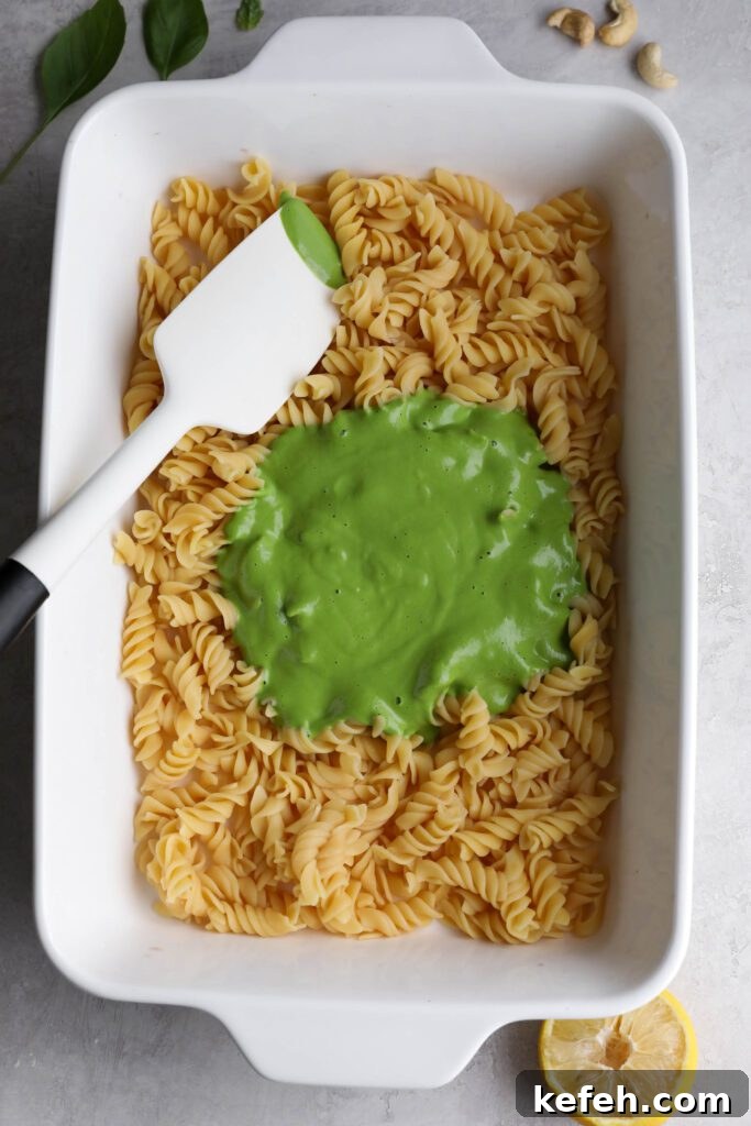 Baked Green Pesto Pasta Casserole Recipe 4 chickpea noodles in casserole dish topped with basil pesto with spatula