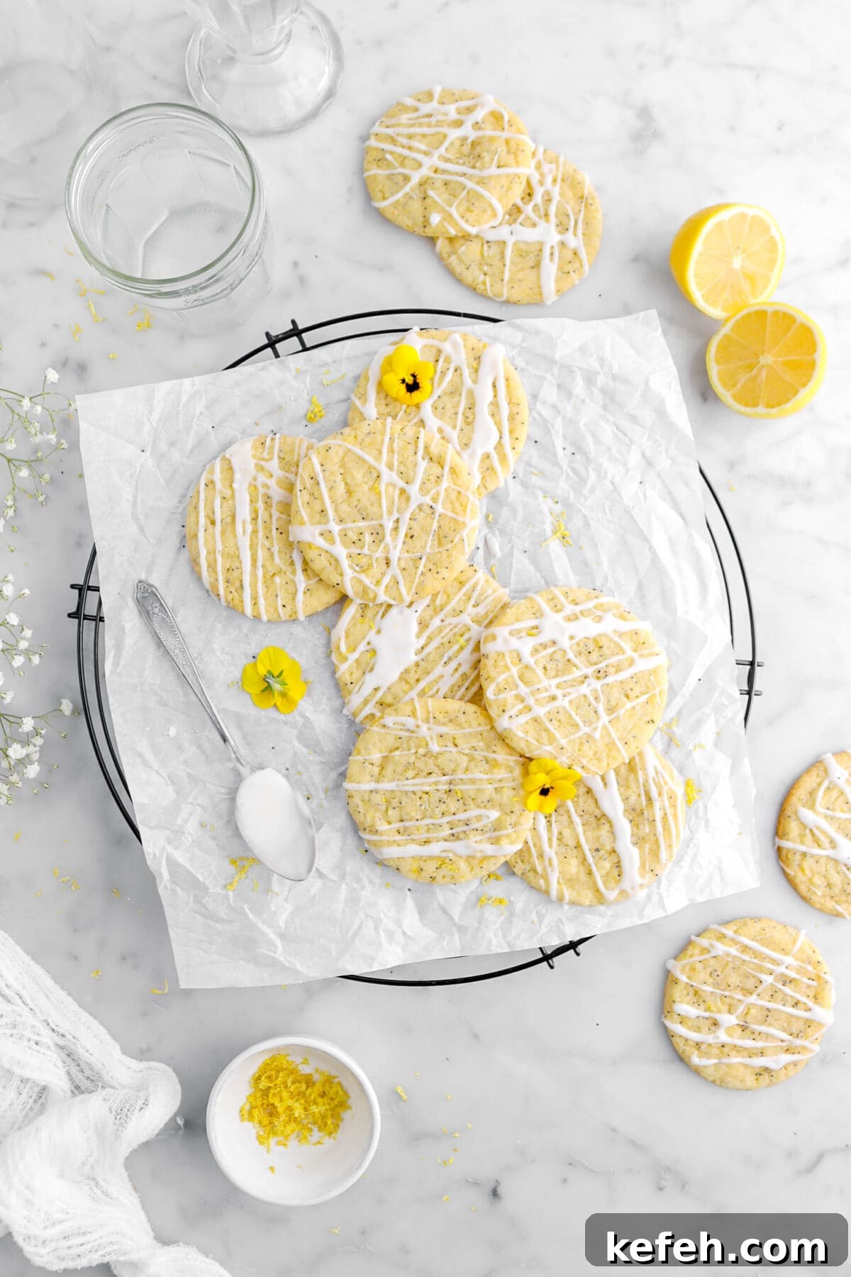 Lemon Poppy Seed Cookies with Lemon Drizzle Recipe 12 overhead shot of seven lemon poppy seed cookies on parchment lined cooling rack, with four more cookies and lemon halves around on marble surface with bowl of lemon zest.