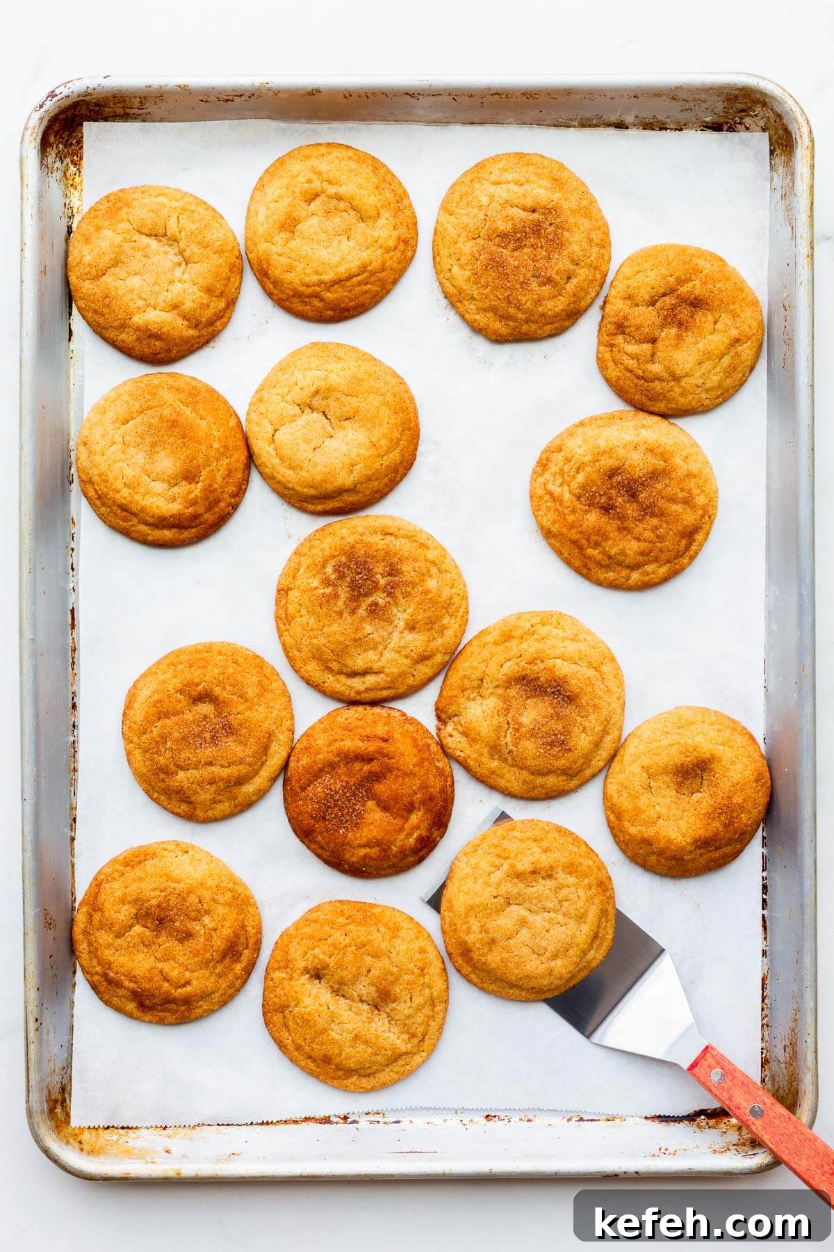 Classic Cinnamon Sugar Snickerdoodle Cookies 6 Using a spatula to lift freshly baked snickerdoodle cookies off a cookie tray.