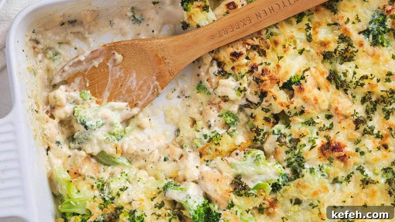 25 Low-Carb Dinners Even Carb Lovers Can't Resist 18 A wooden spoon scooping chicken broccoli alfredo casserole out of a serving dish.