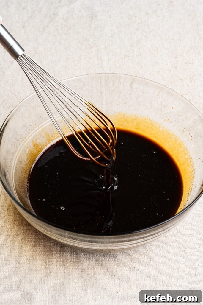 Classic Moist Gingerbread Cake Recipe 4 A wire whisk mixing molasses and coffee together in a bowl.