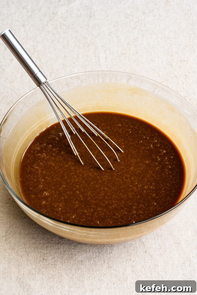 Classic Moist Gingerbread Cake Recipe 6 Liquid cake ingredients in a mixing bowl with a whisk.